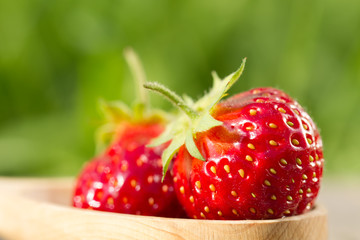 ripe fresh strawberries in spoon on wooden background, close up