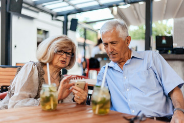 Fototapeta na wymiar Mature Couple In Cafe Using Technology