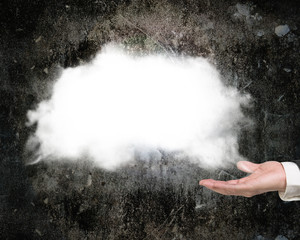 Male hand showing white cloud with dark concrete wall