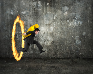 Businessman carrying golden dollar sign jumping through fire hoo © TSUNG-LIN WU