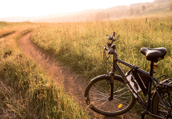 Fototapeta na wymiar black country bicycle at sunrise or sunset