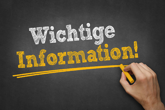 Hand schreibt Text "Wichtige Information!" auf schwarze Kreidetafel