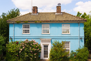 Blue country house with white windows surronded by garden