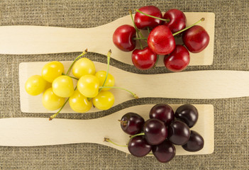 Colorful cherries in a wooden spatula on a natural fabric