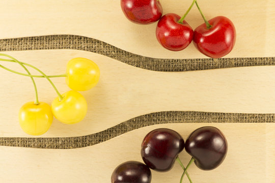 Colorful cherries in a wooden spatula on a natural fabric