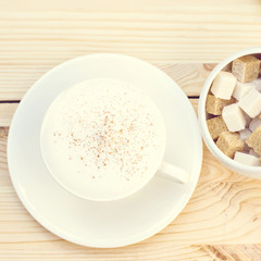 Classic foamy cappuccino in on a  wood table. Detail. From above. A cup of cappuccino