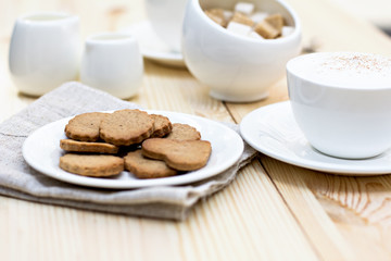 Ginger biscuits, cinnamon, a cup of hot coffee. Walnuts, hazelnuts on a wooden background