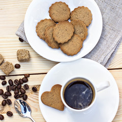 Ginger biscuits, cinnamon, a cup of hot coffee. Walnuts, hazelnuts on a wooden background