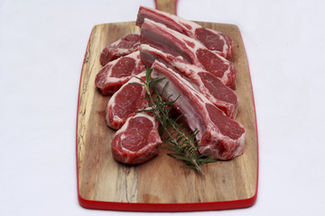 Raw lamb cutlets with rosemary on chopping board
