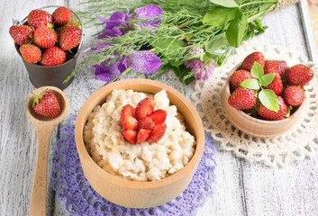 Oatmeal with strawberries in the wooden bowl