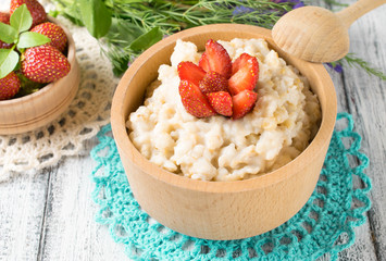 Oatmeal with strawberries in the wooden bowl