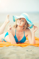 Young lady sunbathing on a beach. Beautiful woman posing at the 