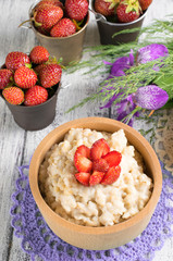 Oatmeal with strawberries in the wooden bowl