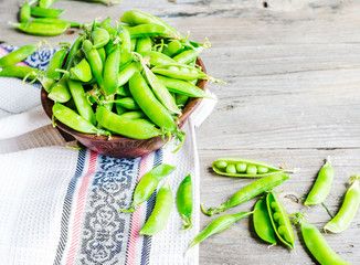 young green peas in the pod, earthenware dish, rustic background