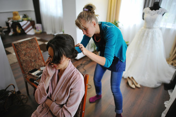 Fototapeta premium Young brunette bride applying wedding make-up by make-up artist