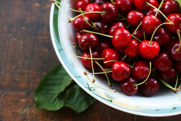 Obstteller, eine Schale auf einem Holzbrett mit frischen roten Kirschen - Süßkirschen Ernte, Obst, vegane Ernährung