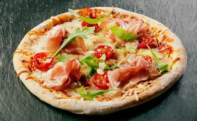 Delicious homemade pizza with ham and rocket