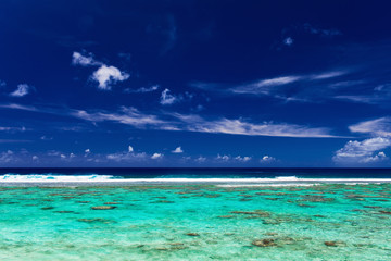 Fototapeta na wymiar Blue sky and surf beach on a coral reef, tropical island