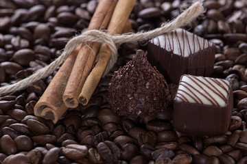 Chocolate with cinnamon sticks on coffee background, selective focus