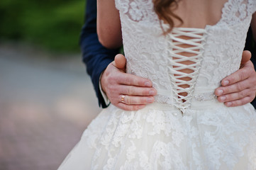 hands of groom who gently holds his wife's waist