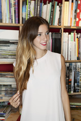 Chica estudiante joven sonriente en la biblioteca