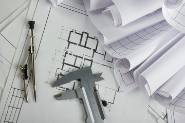 Architectural project, blueprints, blueprint rolls and divider compass, calipers, folding ruler on plans Engineering tools view from the top. Copy space. Construction background.