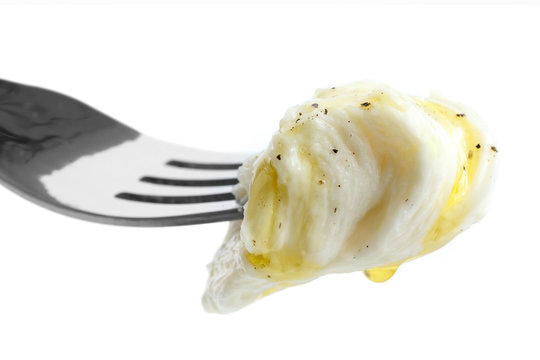 Mouthful of torn mozzarella on fork with oil and pepper. Isolate