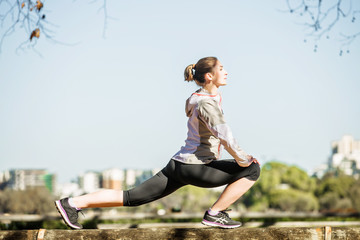 Young fit girl stretching out on bench before exercising in