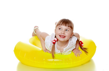Happy joyful blonde girl with pigtails is on a yellow inflatable