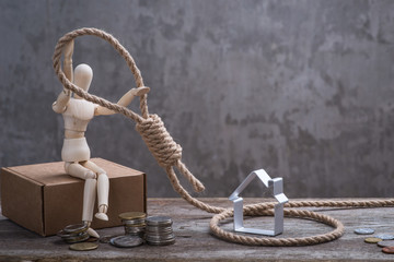 Small wooden dummy sitting with hangman's noose, house and coins