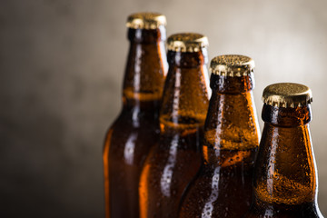 Freshly brewed beer bottles in a row over the grey concrete wall