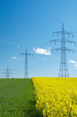 Stromleitungen - Hochspannungsleitungen &uuml;ber Rapsfeld und Getreidefeld