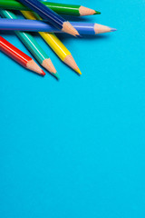 A bunch of color pencils on a blue surface