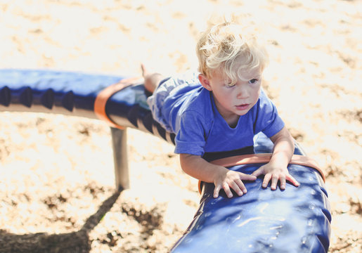 Boy playing on a playground padded spinner in the park, Calfornia, USA
