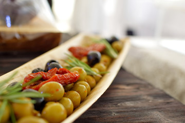 black and green olives, herbs, sun-dried tomatoes in an oblong d