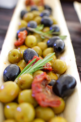 black and green olives, herbs, sun-dried tomatoes in an oblong d