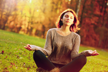 young girl meditating in autumn park