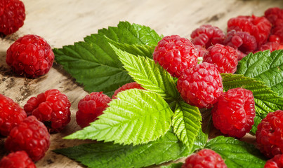 Fresh ripe raspberries with large leaves on the old wooden table