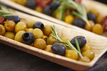 black and green olives, herbs, sun-dried tomatoes in an oblong d