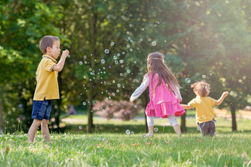 Three children in the park blowing soap bubbles and having fun