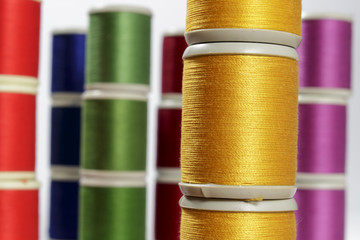 Close-up orange cotton thread bobbins. Other color threads in background