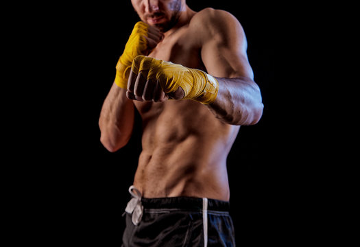 Sportsman kick boxer portrait against black background.