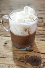 chocolate drink with whipped cream in transparent cup on wooden