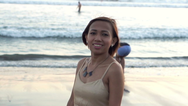 Portrait of young, happy woman walking along beach, slow motion shot at 240fps
