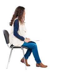 back view of young beautiful  woman sitting on chair.