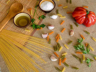 Uncooked dry spaghetti on a rustic surfaces with tomato, garlic,