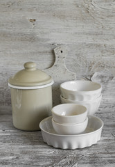 white vintage crockery - enamelled jug, ceramic bowl and baking dish on a light wooden background