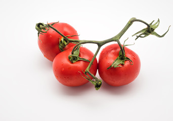 Three red and fresh tomatoes on the vine isolated on white