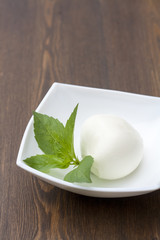 Mozzarella with herbs in a white rectangular bowl on wooden table