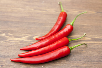 Red chilli pepper with green basil on wooden board